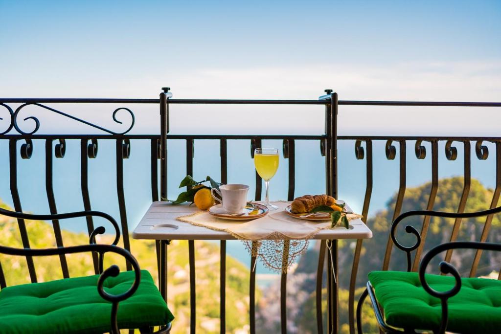un tavolo con un bicchiere di succo d'arancia e un piatto di cibo di CASA BELLAVISTA Scala Minuta Amalfi Coast a Scala