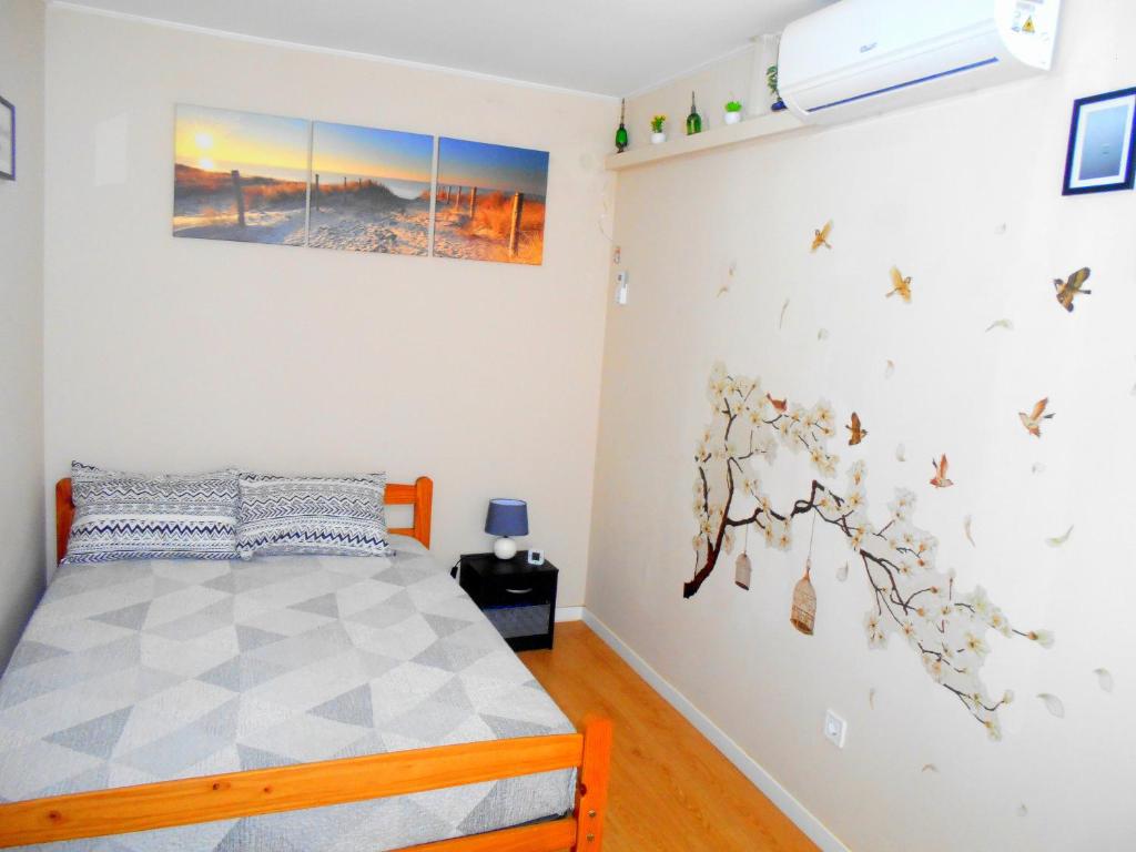 Arade Rooms في Parchal: غرفة نوم مع سرير وورود على الحائط