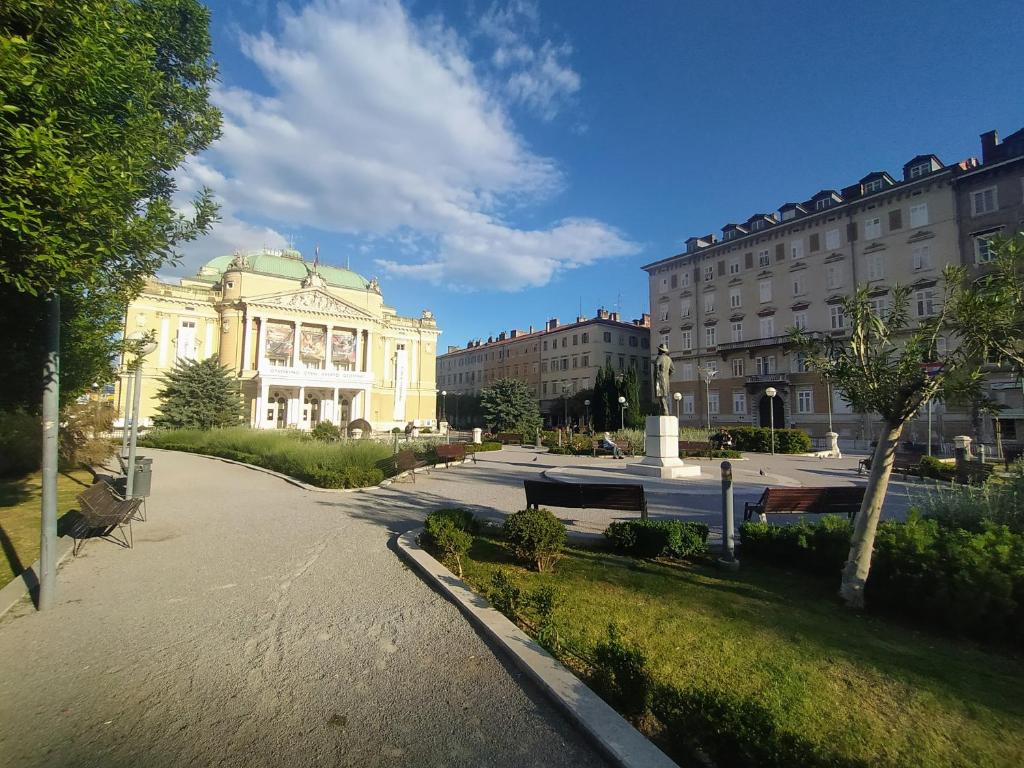 un bâtiment dans un parc à côté de certains bâtiments dans l'établissement Mario City Center Rooms, à Rijeka