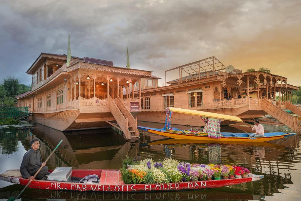 a man in a boat next to a house on the water at WelcomHeritage Gurkha Houseboats in Srīnagar