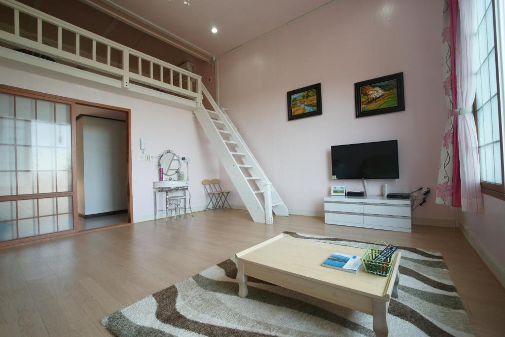 a living room with a staircase and a tv at Dreaming Forest Pension Seogwipo in Seogwipo