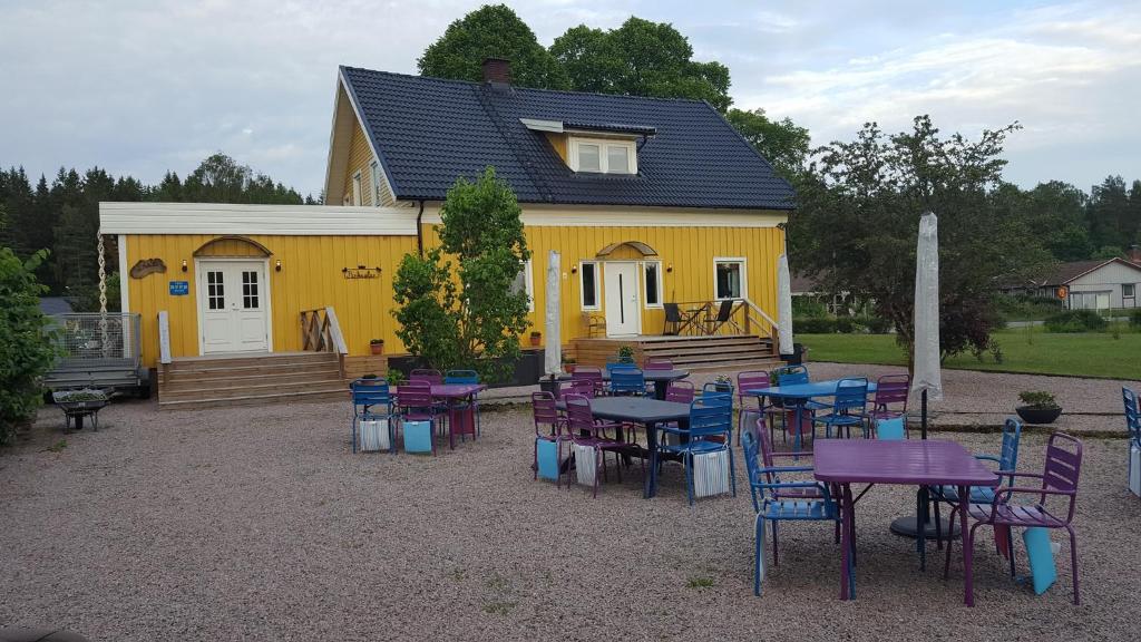 a yellow house with tables and chairs in front of it at B&B Parksäter in Håcksvik