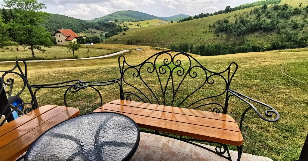 a wooden bench sitting on top of a field at Vikendica Gradina Zlatibor in Čajetina