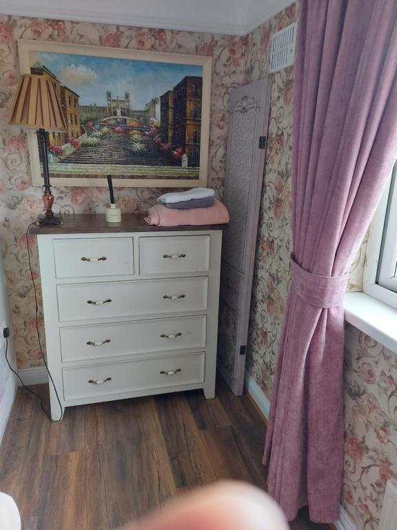 a bedroom with a dresser and a painting on the wall at Luglass house blueball in Blue Ball