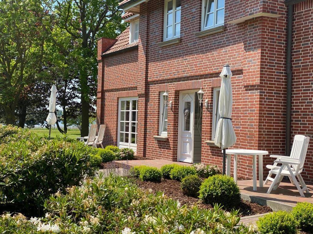 a brick house with two chairs and an umbrella at NTAB10002-FeWo-Moeoevwarder-twee in Neue Tiefe Fehmarn