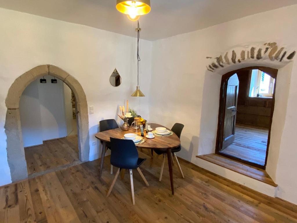 uma sala de jantar com uma mesa de madeira e cadeiras em Appartamento Saeculum em Egna