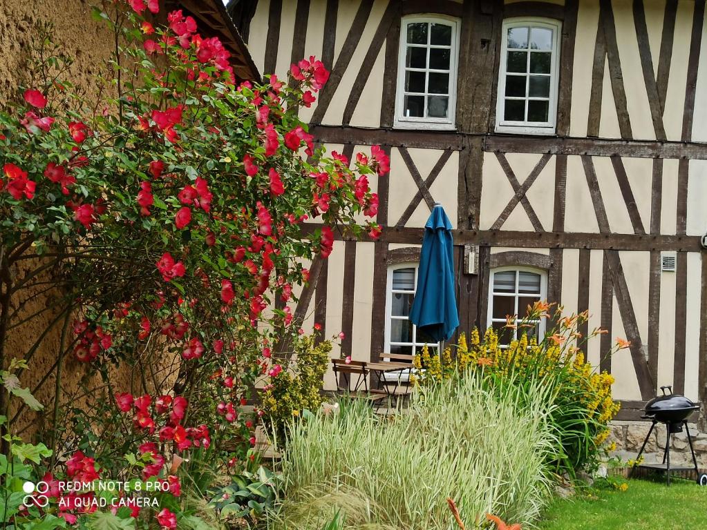 La Colombine في Vascoeuil: منزل به زهور حمراء ومظلة زرقاء