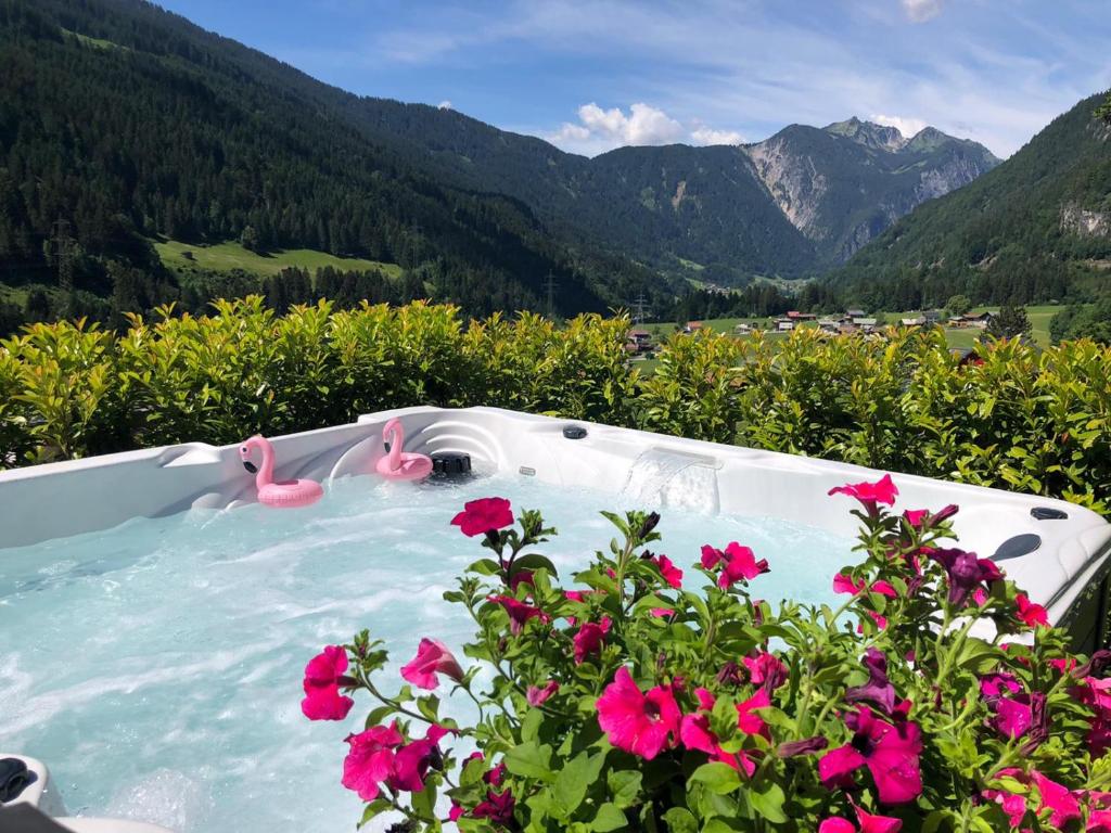 two pink flamingos in a hot tub with flowers at Alpenburg Bergparadies Apartments in Wald am Arlberg