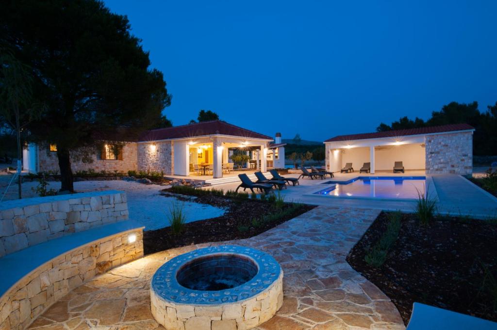 a backyard with a swimming pool and a house at Luxury Villa Nature with heated private pool, sauna & fire pit, a short walk to the beach in Milna