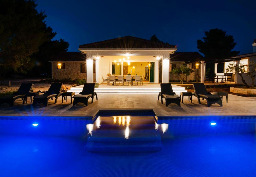 a pool in front of a house at night at Luxury Villa Nature with heated private pool, sauna & fire pit, a short walk to the beach in Milna
