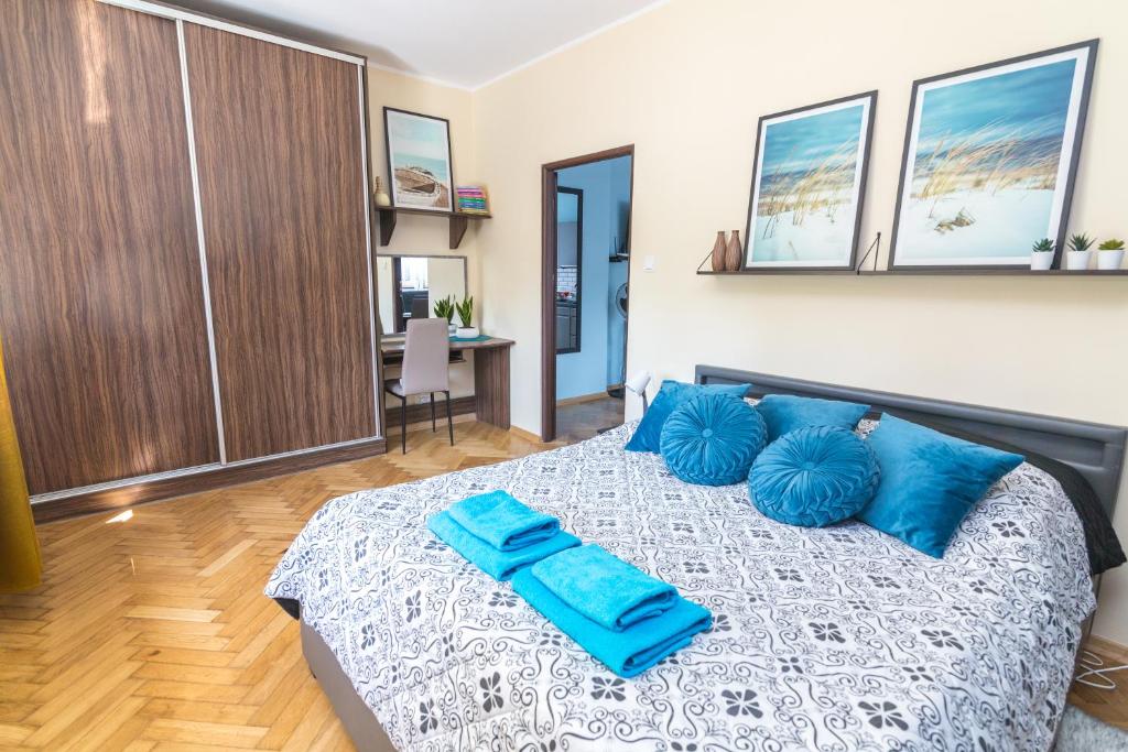 a bedroom with a bed with blue pillows on it at Apartament z jacuzzi in Hel