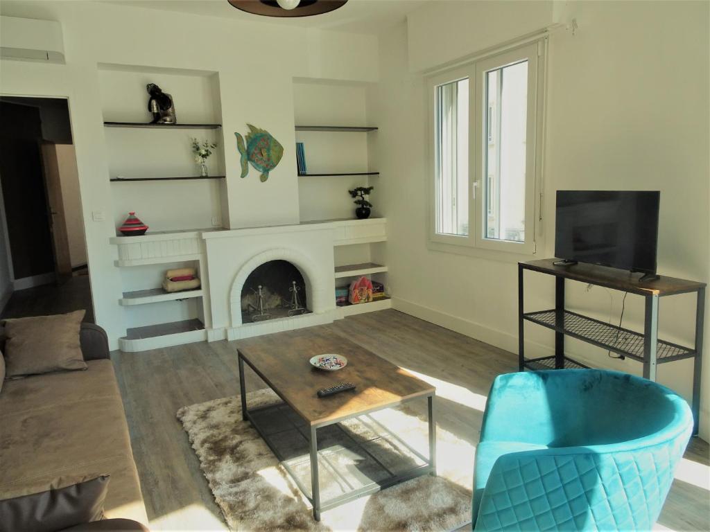 un salon avec une cheminée et une chaise bleue dans l'établissement Appartement Triangle d Or plage-gareTGV-Mairie, à Saint-Raphaël