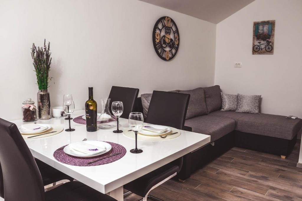 una mesa blanca con copas de vino y un sofá en Apartmani Vučković, en Vodice
