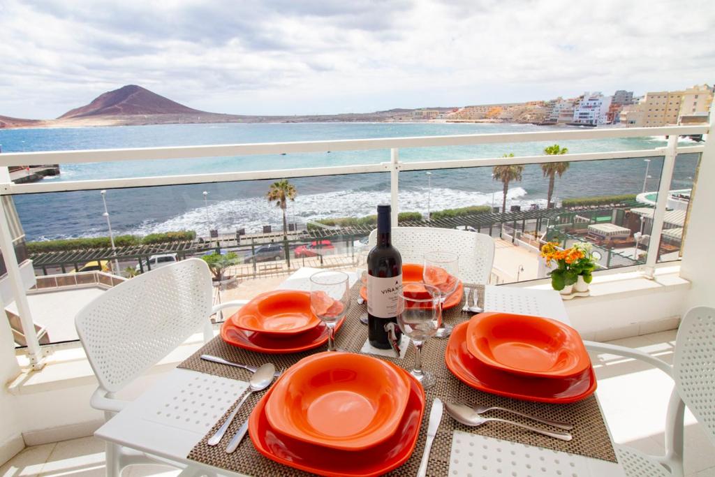 a table with a bottle of wine and a view of the ocean at MEDANO4YOU The Harbour Holiday Home in El Médano