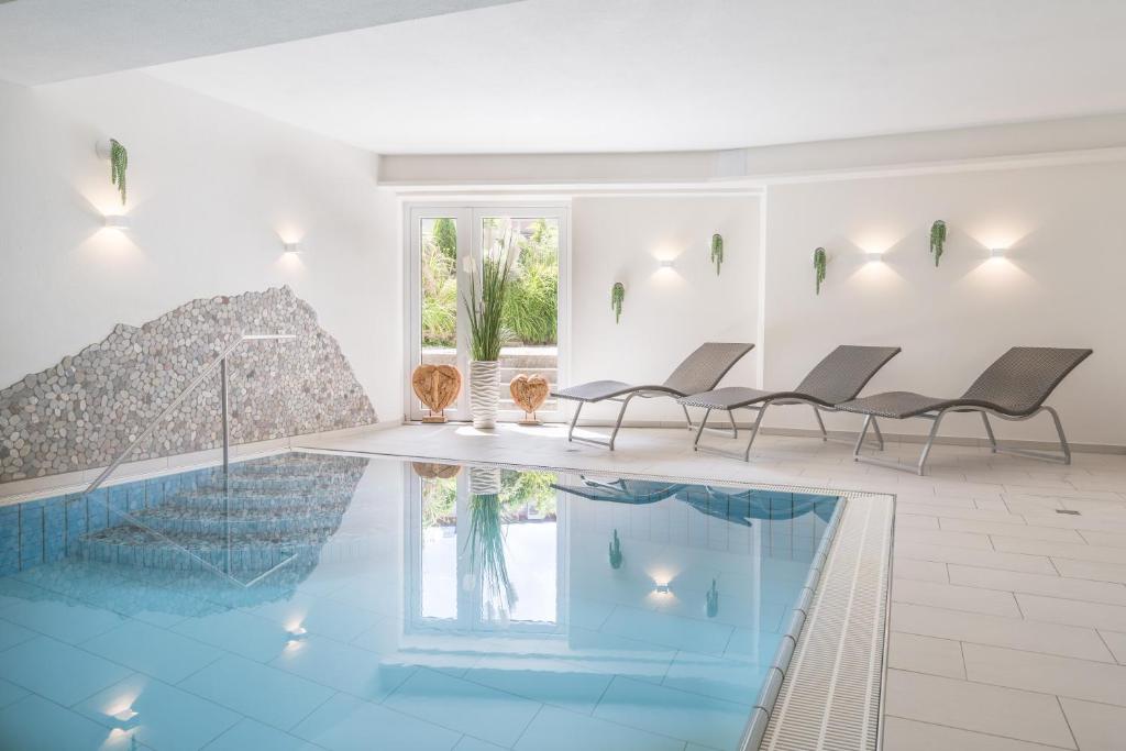 a room with a swimming pool with chairs and a table at Hotel garni Gerberhof ***S in Oberstdorf