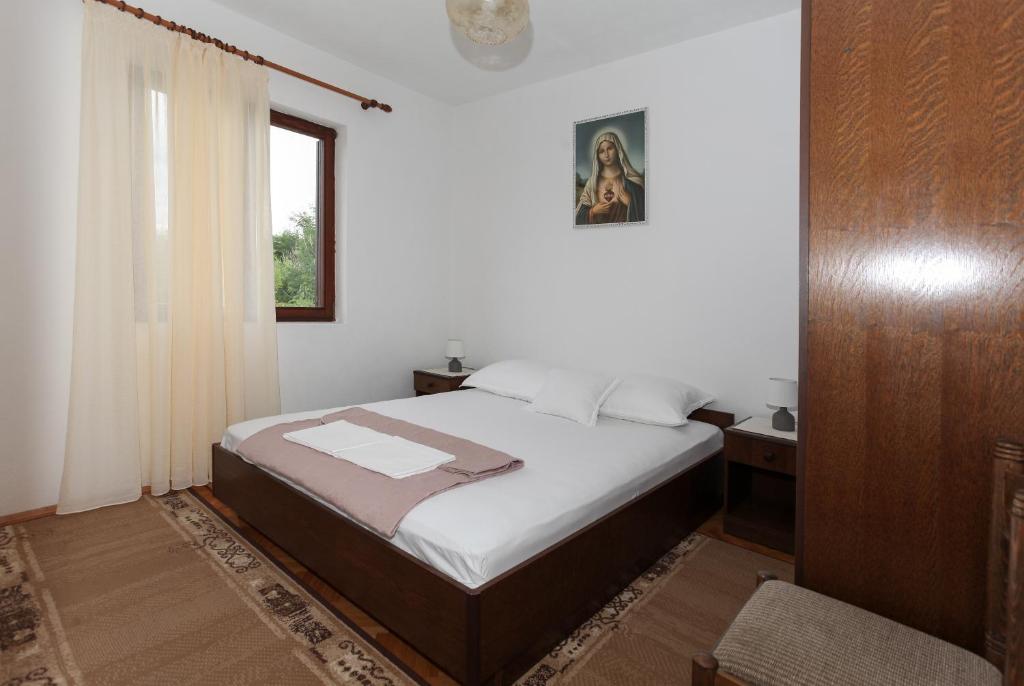 a bedroom with a bed and a window at Apartments Spavalo in Pag