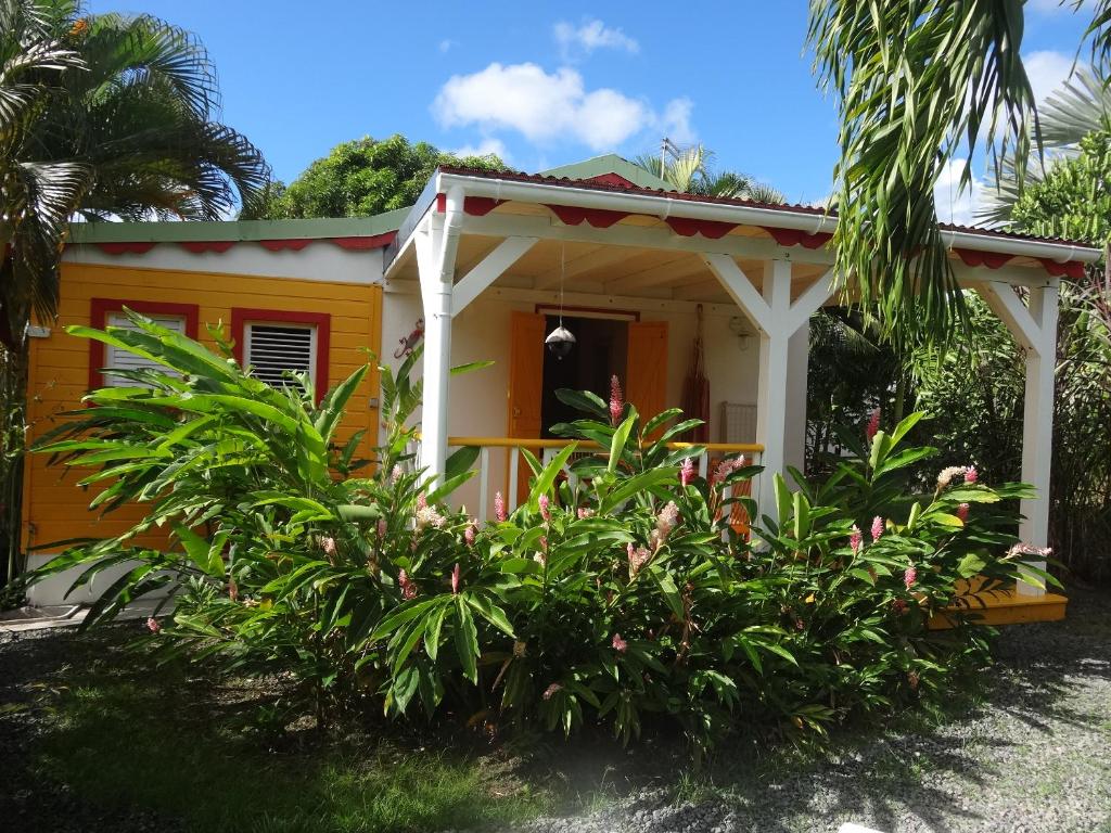 una pequeña casa amarilla con plantas delante en Gîte Zandoli Koko, en Sainte-Anne
