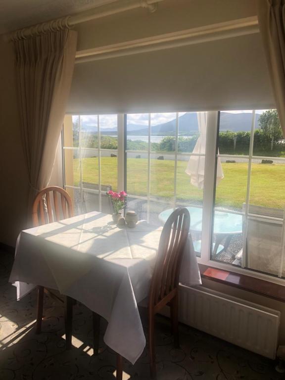 uma mesa com duas cadeiras e uma grande janela em Murrayville B&B em Achill Sound