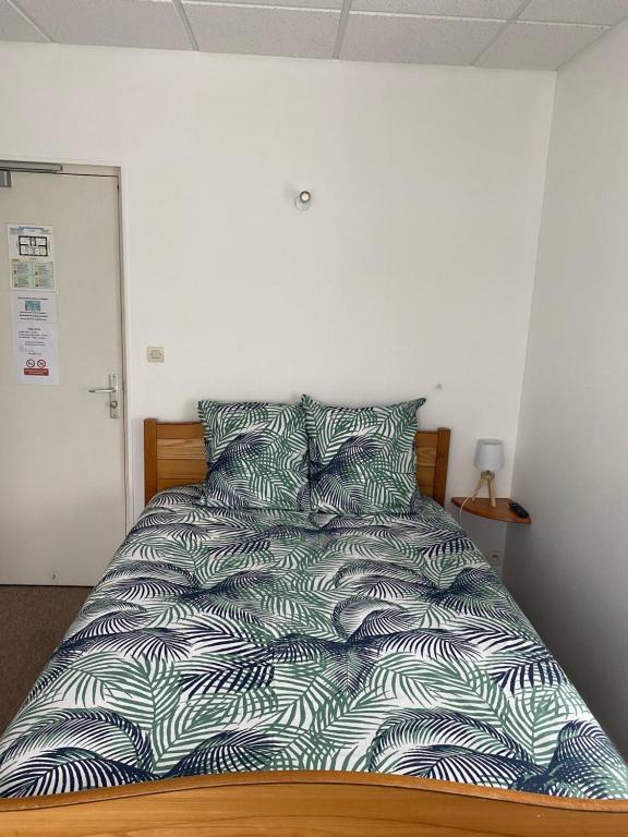 uma cama com um edredão azul e branco num quarto em Hotel le faubourg em La Guerche-de-Bretagne