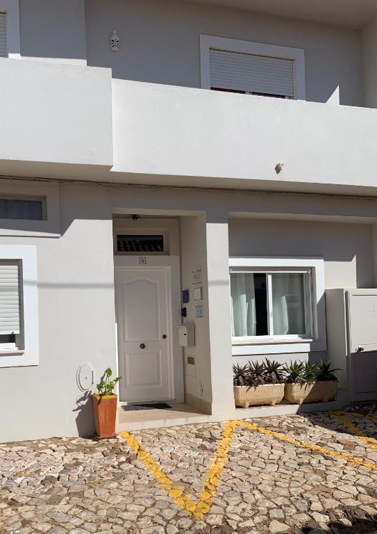 a white building with a door and a window at Casa da Aldeia - Guest House in Odiáxere