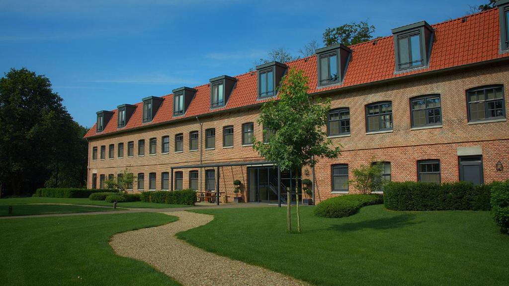 een groot bakstenen gebouw met een groen gazon ervoor bij Hotel de Kastanjefabriek in Eibergen