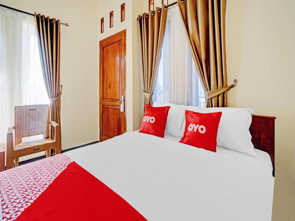 a bedroom with a large bed with red pillows at OYO 90472 Villa Dua Dua in Tlekung
