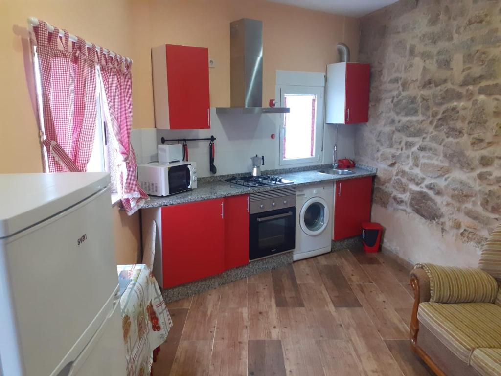 een keuken met rode kasten, een fornuis en een magnetron bij Apartamento en zona rustica de Camariñas in Camariñas