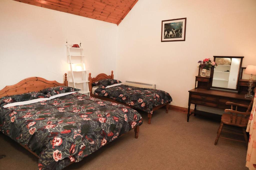 a bedroom with two beds and a table and a mirror at Wisteria Cottage in Ballyconnell