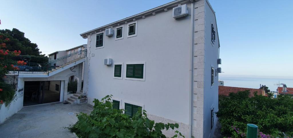 un edificio blanco con persianas verdes. en Apartment Villa Mirna, en Makarska