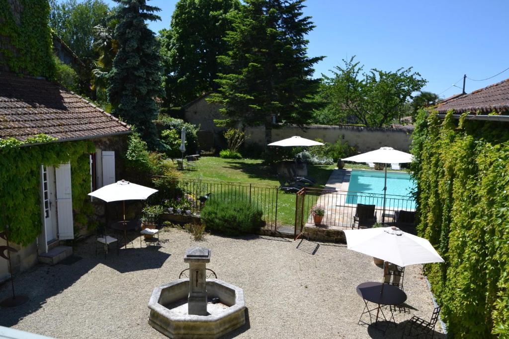 un patio trasero con una fuente y sombrillas y una piscina en La Baguenaude, en Marciac