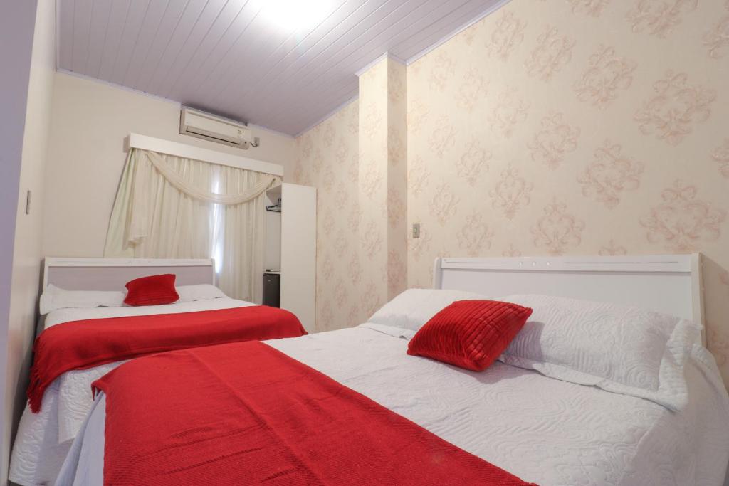 two beds in a room with red and white at Pousada Tia Eni in Gramado