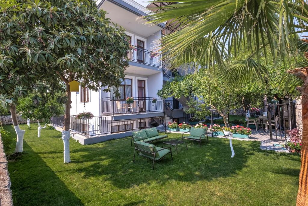 un jardin avec des chaises et des tables en face d'un bâtiment dans l'établissement Sayan Apart Hotel, à Kemer