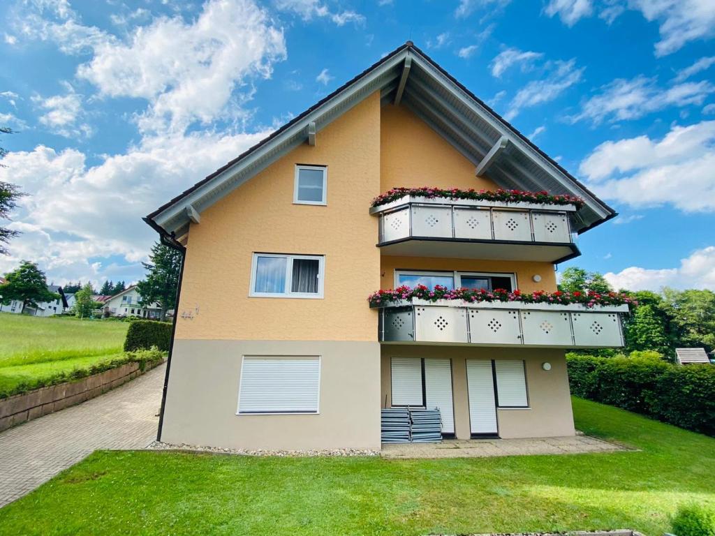 ein gelbes Haus mit einem Balkon mit Blumen darauf in der Unterkunft Ferienwohnung Heide in Freudenstadt