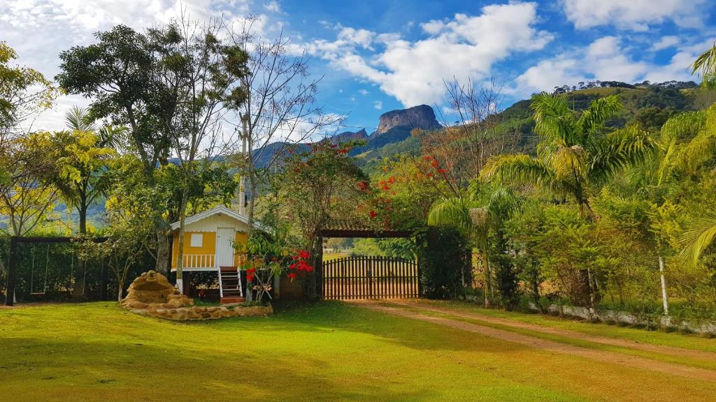 een huis met een poort in een tuin met een berg bij Chalés Poly in São Bento do Sapucaí