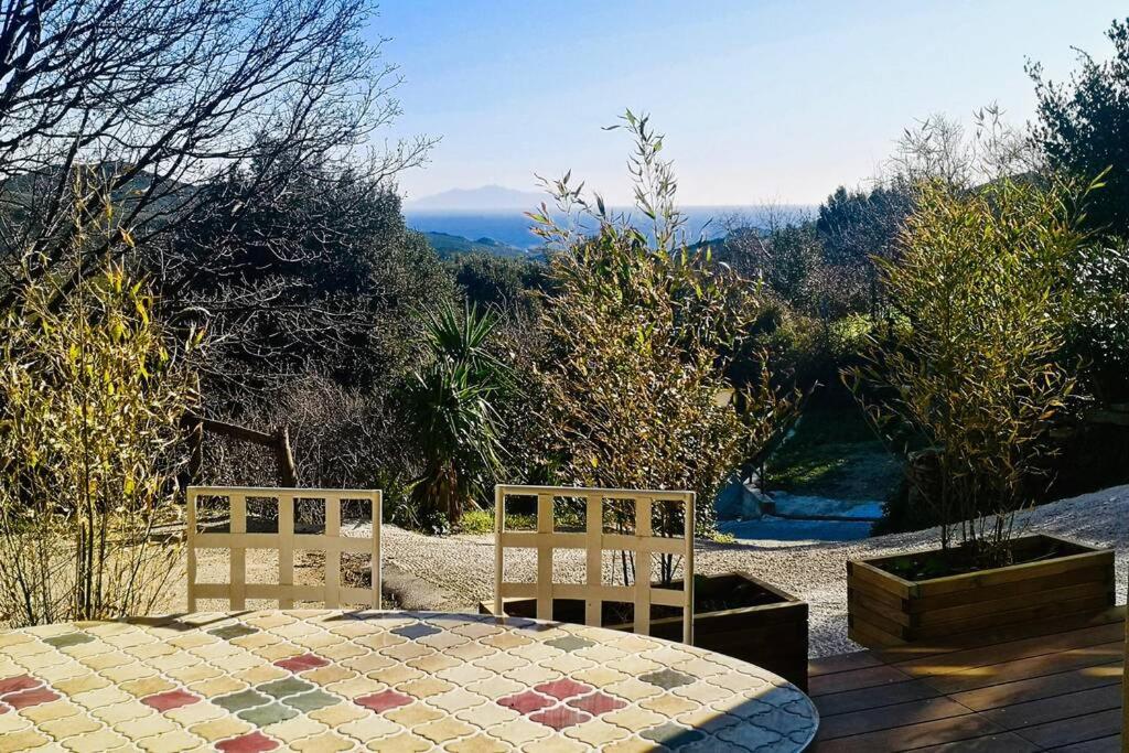 una mesa y 2 sillas en un patio con vistas en Gîte indépendant dans villa entre mer et maquis, en Sisco