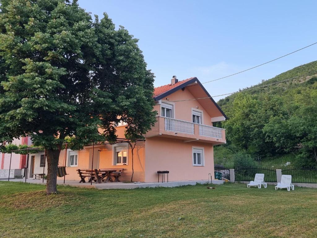 a pink house with a tree and a table and benches at Apartmani Svitavac in Trebinje