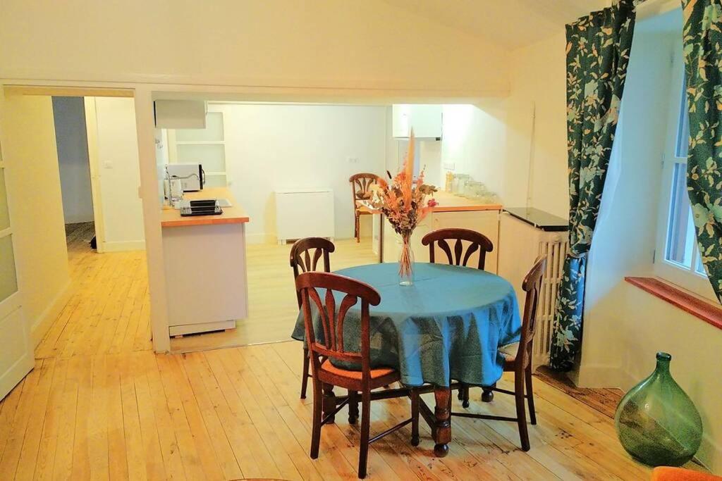 a dining room with a table and chairs and a kitchen at Gîte de la chapelle, au coeur de la cité médiévale in Allègre