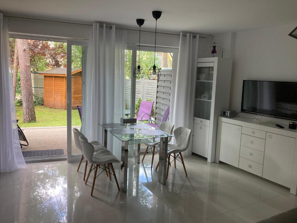 une salle à manger avec une table et des chaises en verre dans l'établissement Apartament 8, à Pobierowo