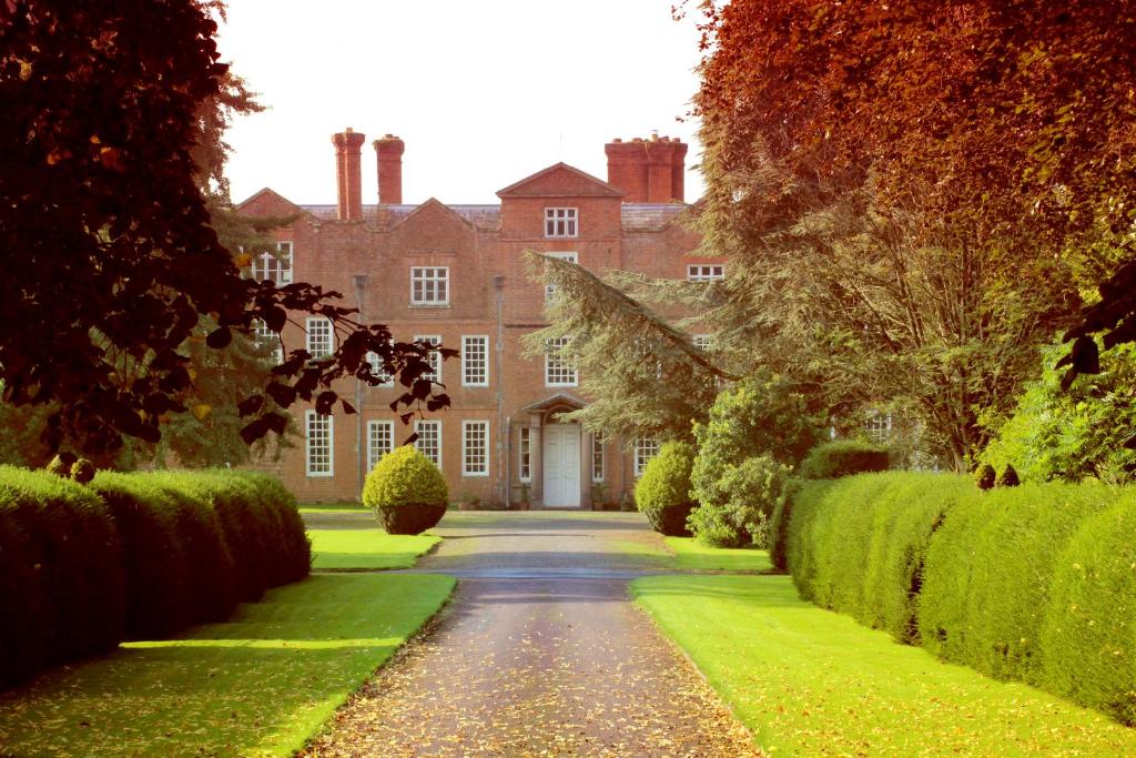 una entrada que conduce a una casa grande con arbustos verdes en Henley Hall, Ludlow, en Ludlow