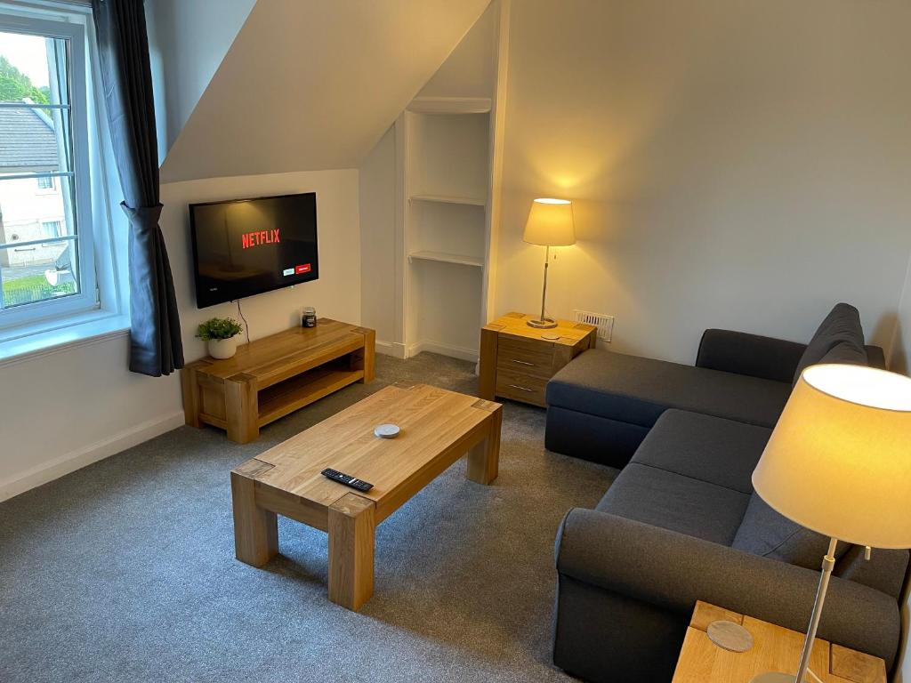 a living room with a couch and a tv at Premier 3 Bed Flat D in Broxburn