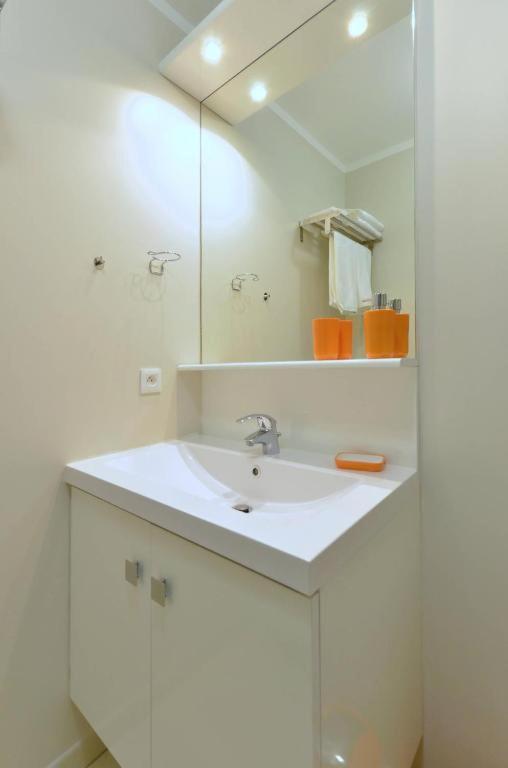a white bathroom with a sink and a mirror at Orange Studio Paris Disneyland in Serris