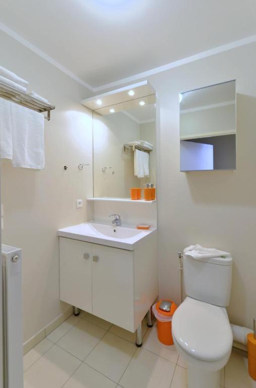 a white bathroom with a toilet and a sink at Orange Studio Paris Disneyland in Serris