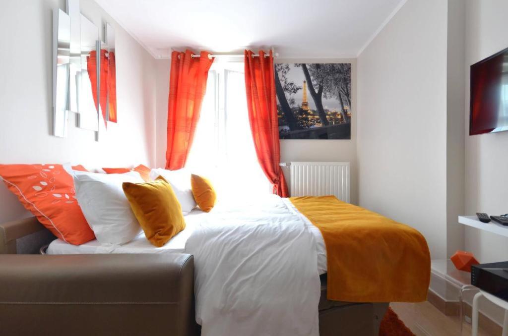 a bedroom with a bed and a window with orange curtains at Orange Studio Paris Disneyland in Serris