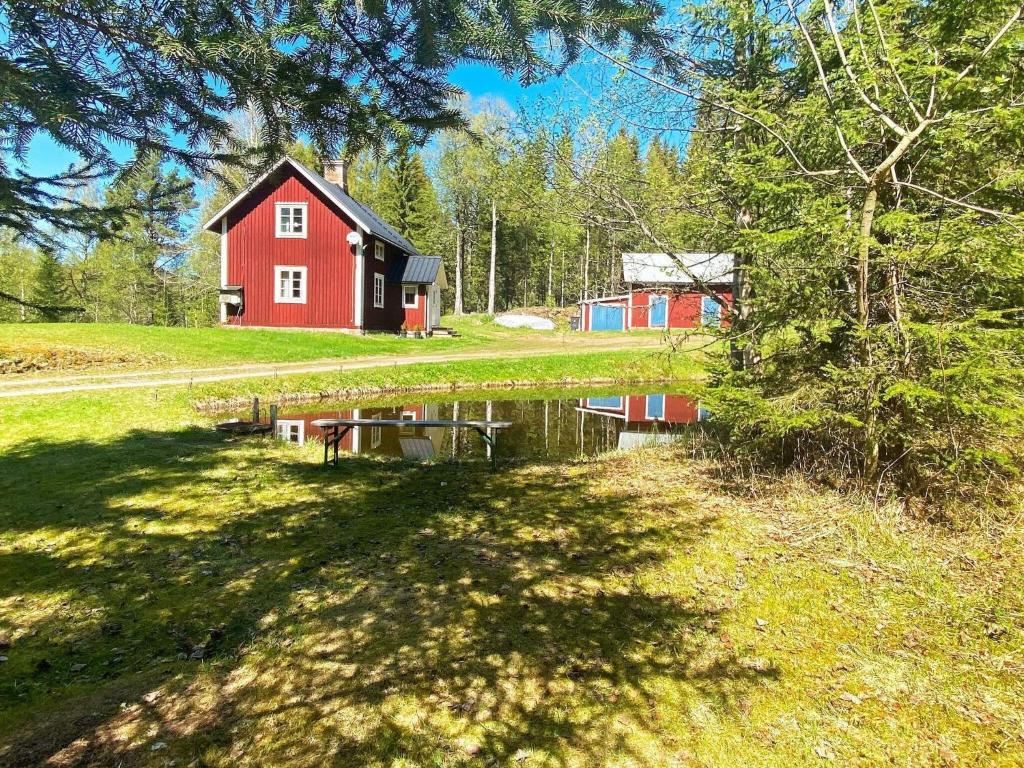 a red barn and a pond in front of a house at 6 person holiday home in TRANSTRAND in Transtrand