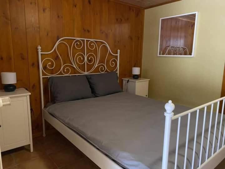 uma cama branca num quarto com paredes de madeira em Gîte Little Creek em Hamoir