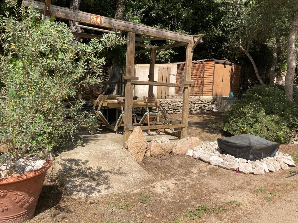 een houten pergola met een houten stoel in een tuin bij Petite maison de campagne in Bonifacio