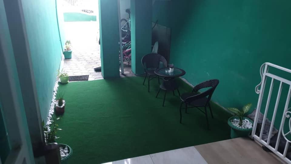 a room with a green floor with chairs and a table at Aimé Anaïs in Abaga