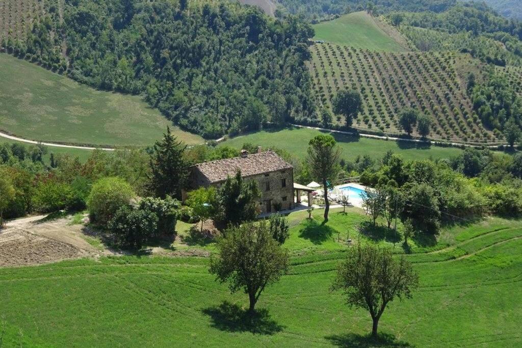 an aerial view of a house in a green field at Ca La Piera, Le Marche, Italy in Piandimeleto