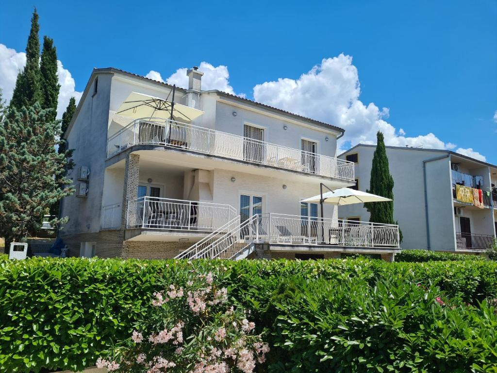 a large white house with a balcony and bushes at Apartments Elizabeta in Dramalj