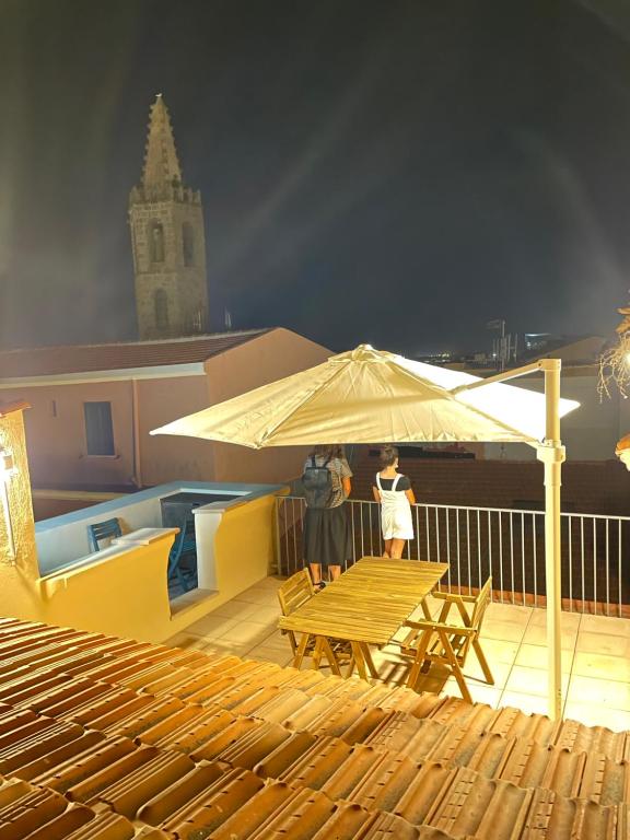 two people standing under an umbrella on a deck at Gioberti 25 in Alghero